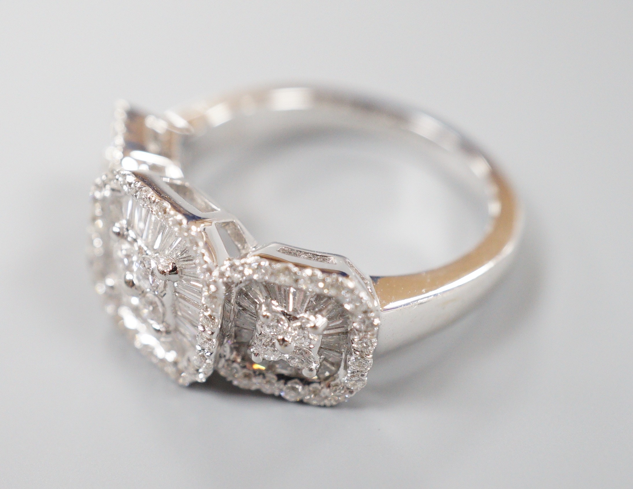 A modern 750 white metal, trapeze and round cut diamond set triple cluster dress ring, size M, gross weight 7 grams